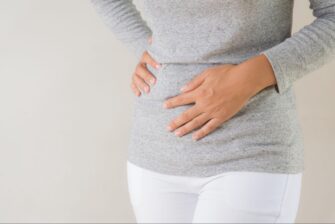 卵子凍結の副作用をイメージさせるお腹を抑える女性の画像