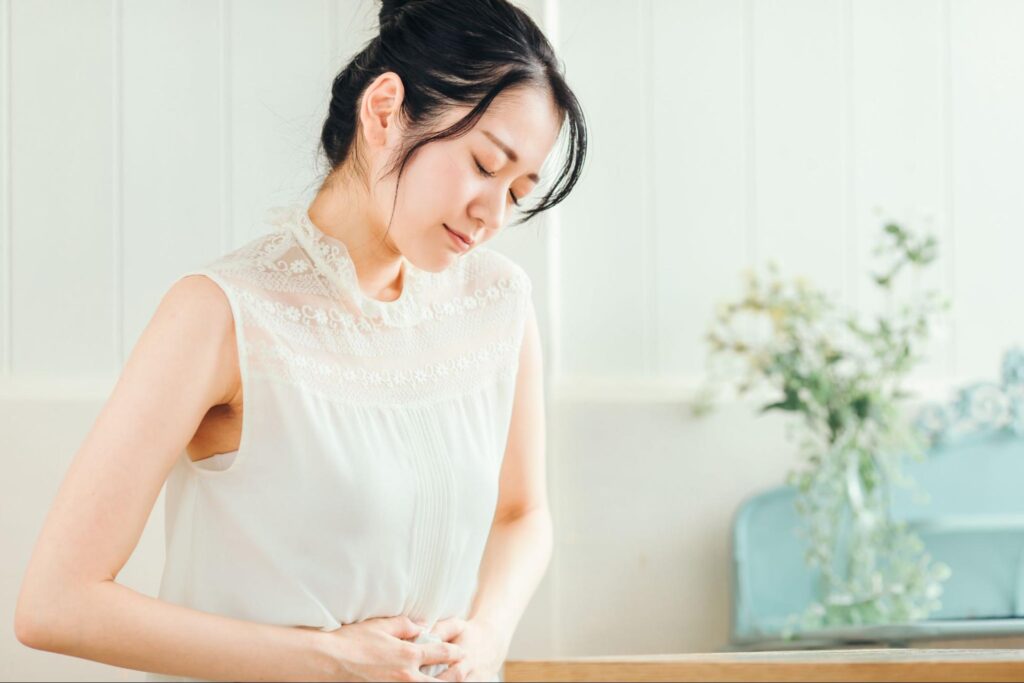 卵子凍結の副作用をイメージさせるお腹を抑える女性の画像