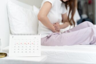 ベッドでお腹を押さえる女性とカレンダーの画像