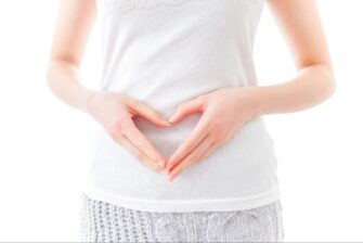 お腹の前で両手でハートマークを作る女性の画像