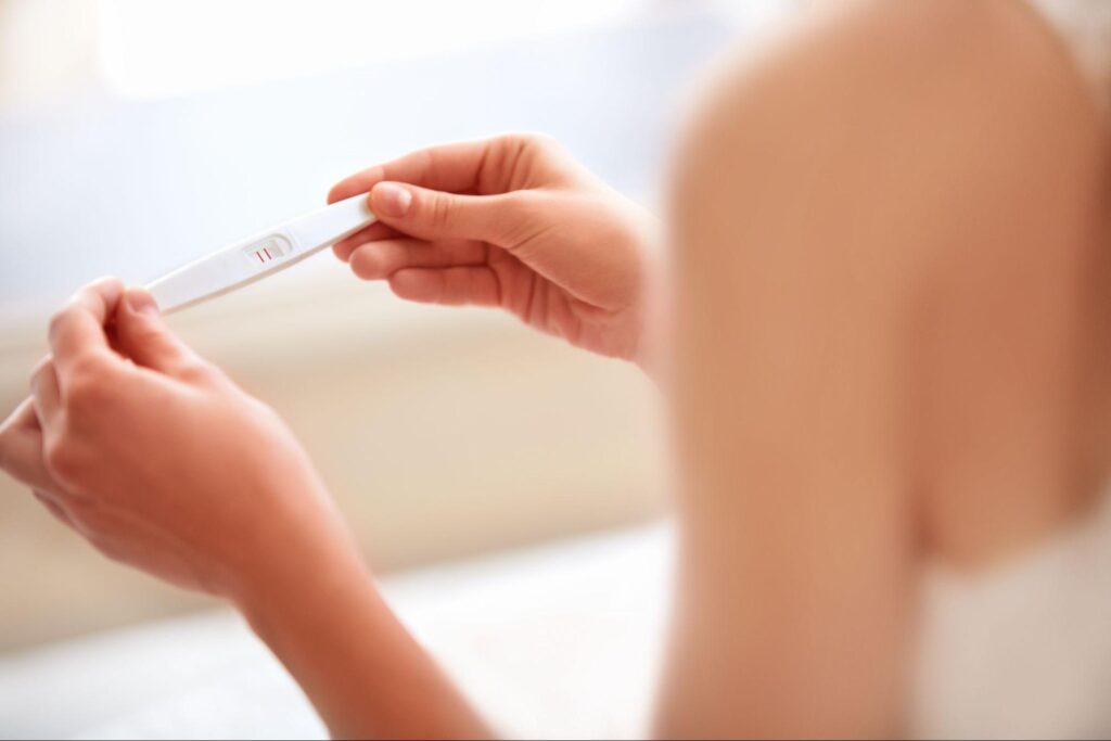 妊娠検査薬の結果を見ている女性の画像